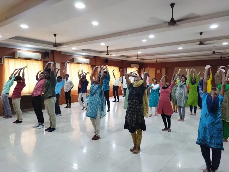 Students standing with arms raised in Surya Namaskar